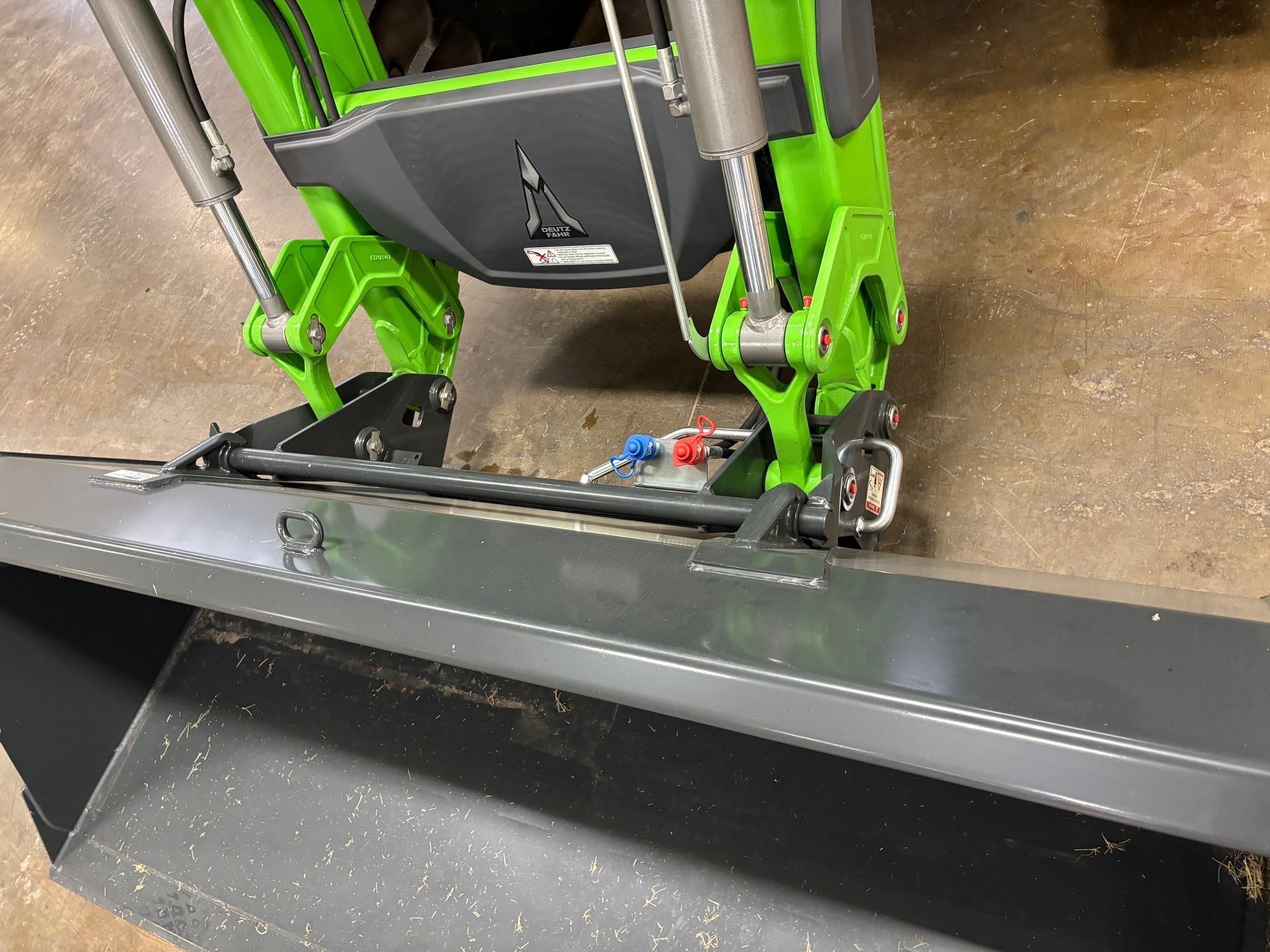 Green and black tractor front-end loader and bucket, parked on a surface.