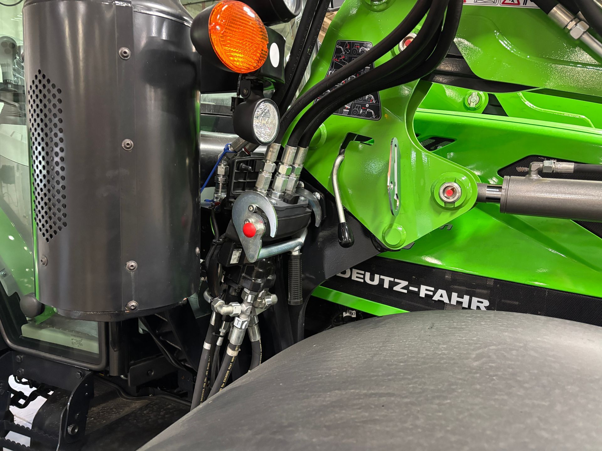 Close-up of a green Deutz-Fahr tractor showing hydraulic lines, lights, and a tow hook.