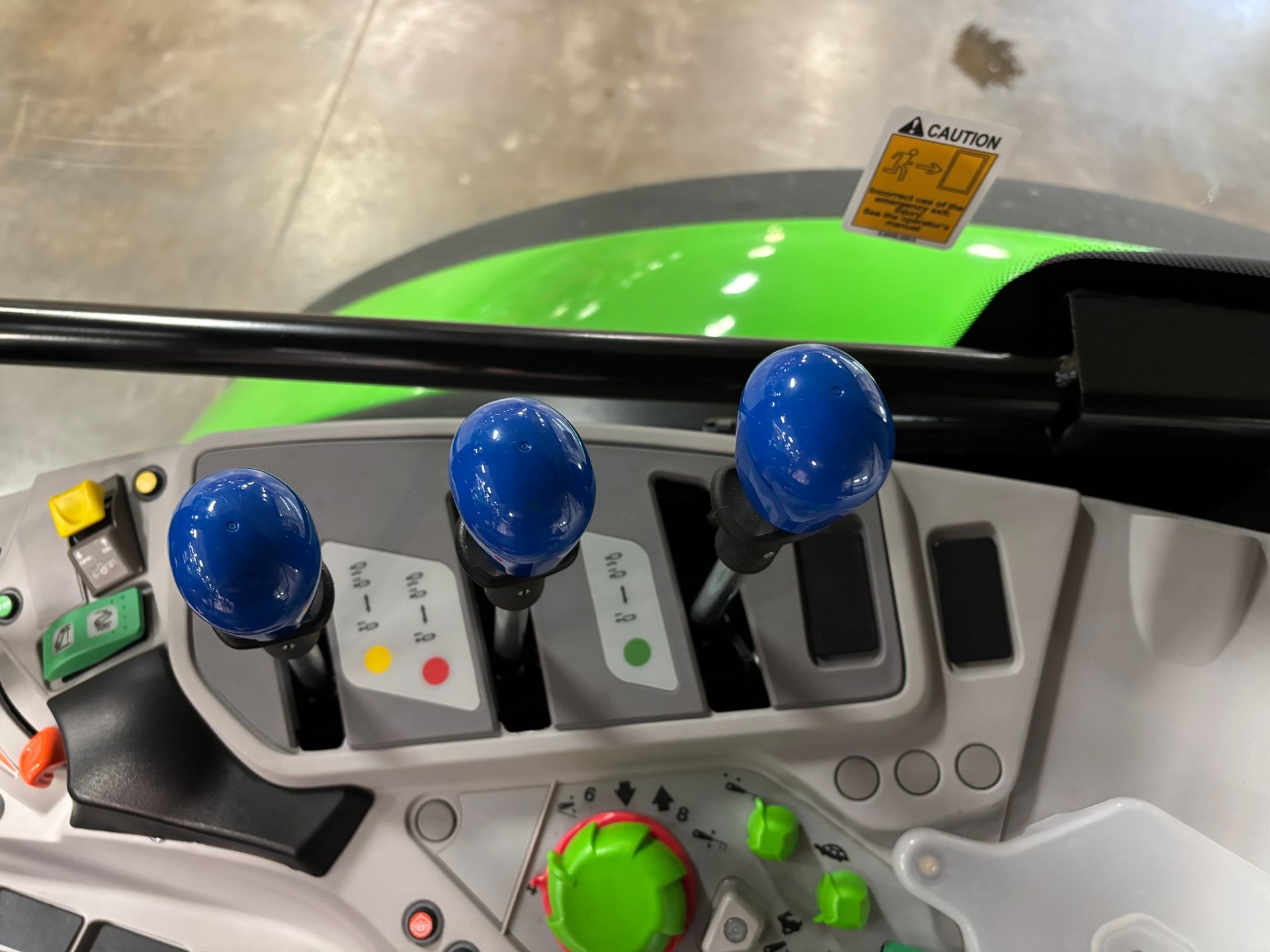 Tractor control panel with three blue-knobbed levers and green accents.