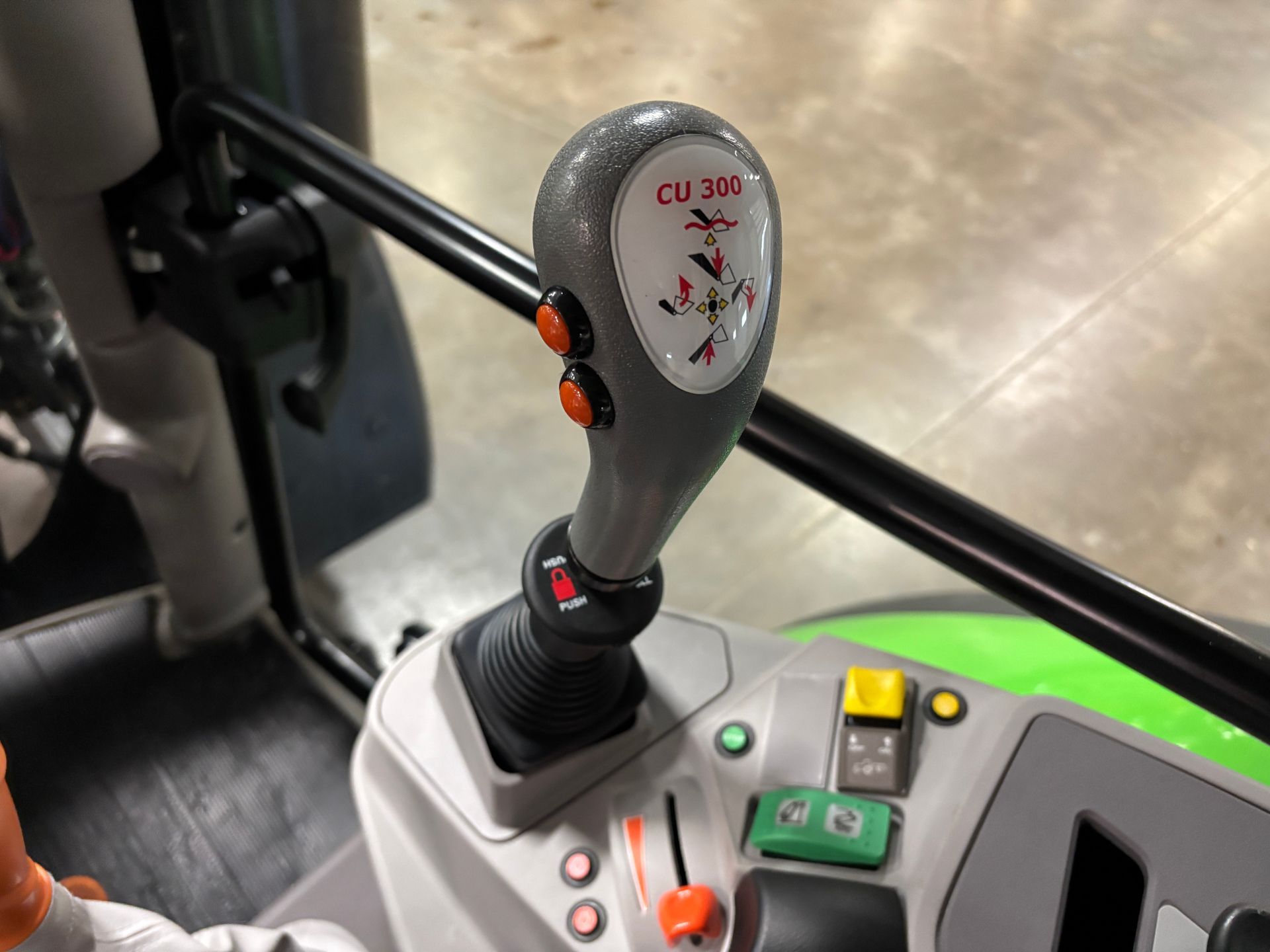 Close-up of a tractor joystick with orange buttons and symbols.