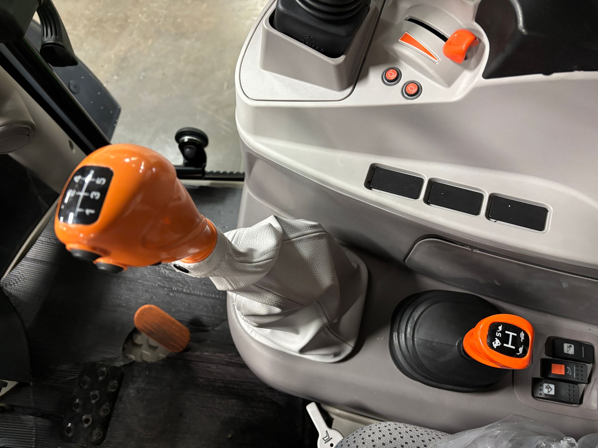 Orange and black tractor gear shift with various controls and switches.