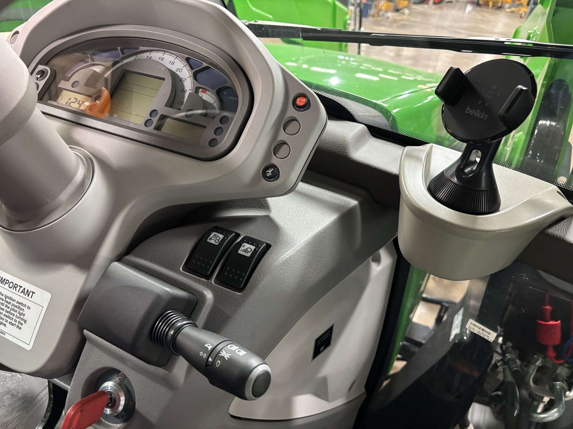 Dashboard of a tractor with gauges, switches, and a phone holder.