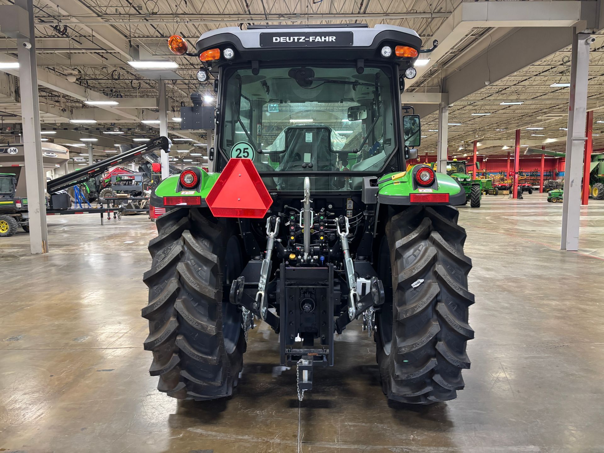 Rear view of a Deutz-Fahr tractor with large tires, red triangle, and a green and black cab.