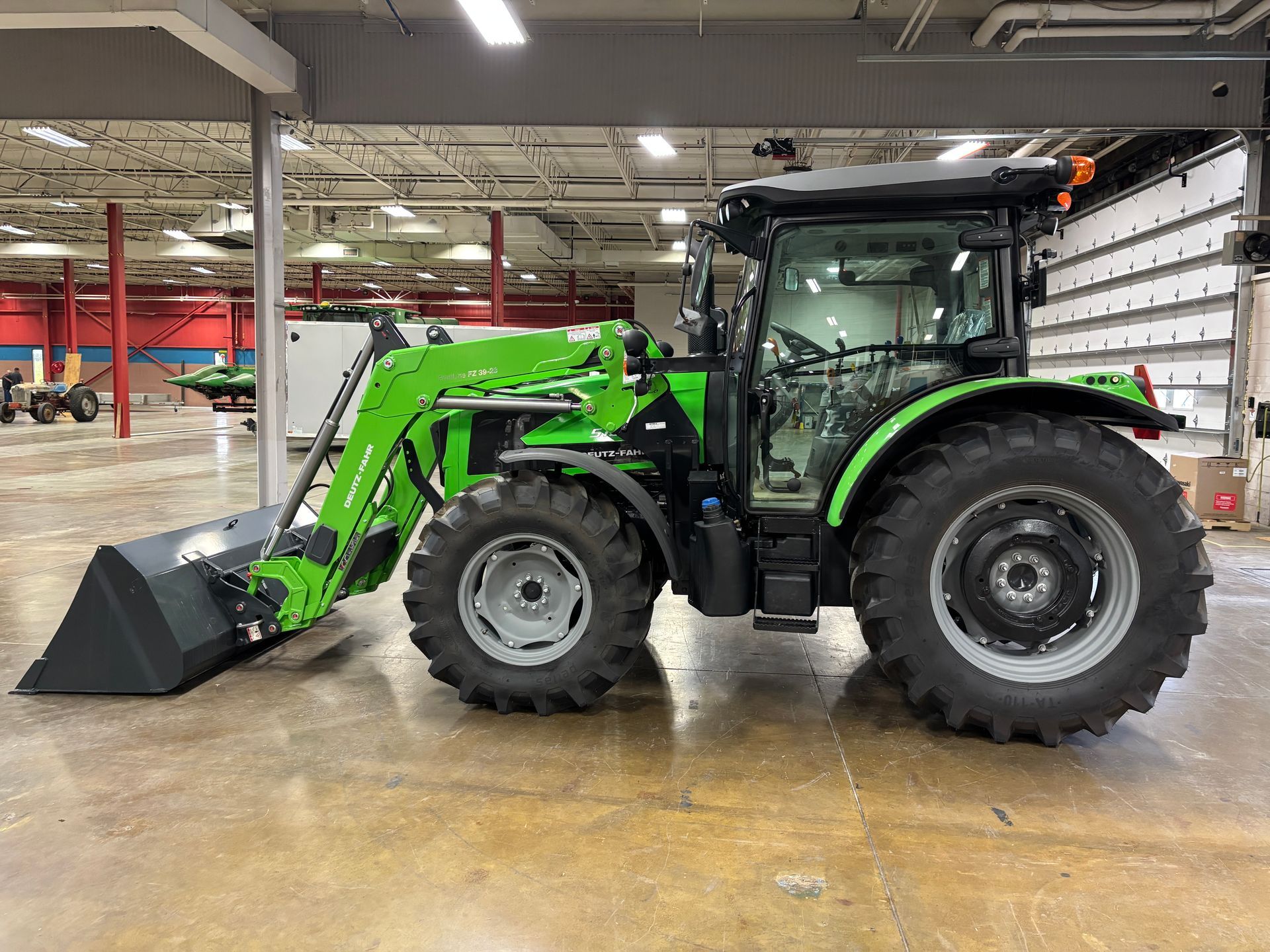 Green Deutz-Fahr tractor with front loader inside a warehouse.