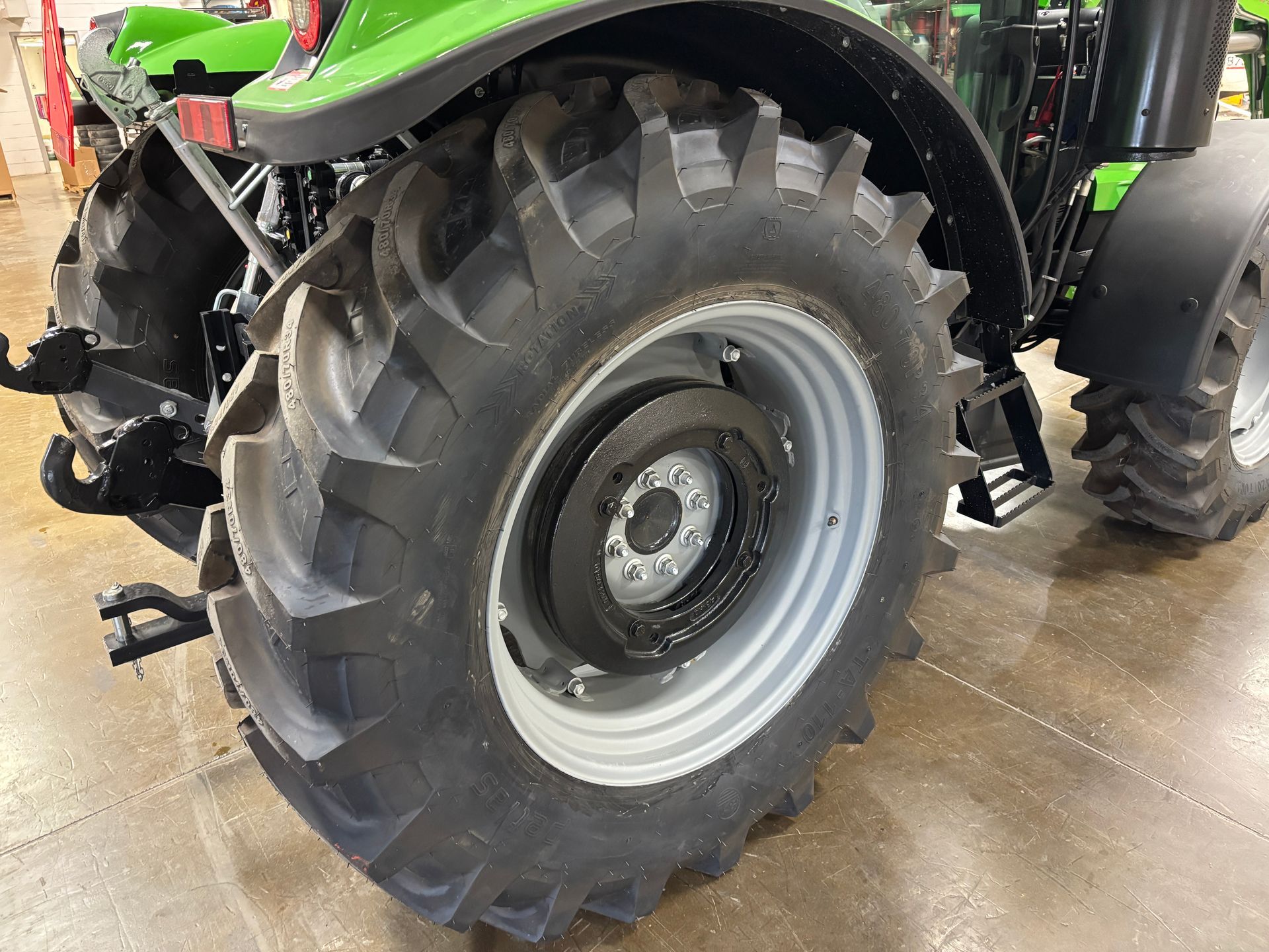 Close-up of a large tractor tire and wheel on a grey rim.