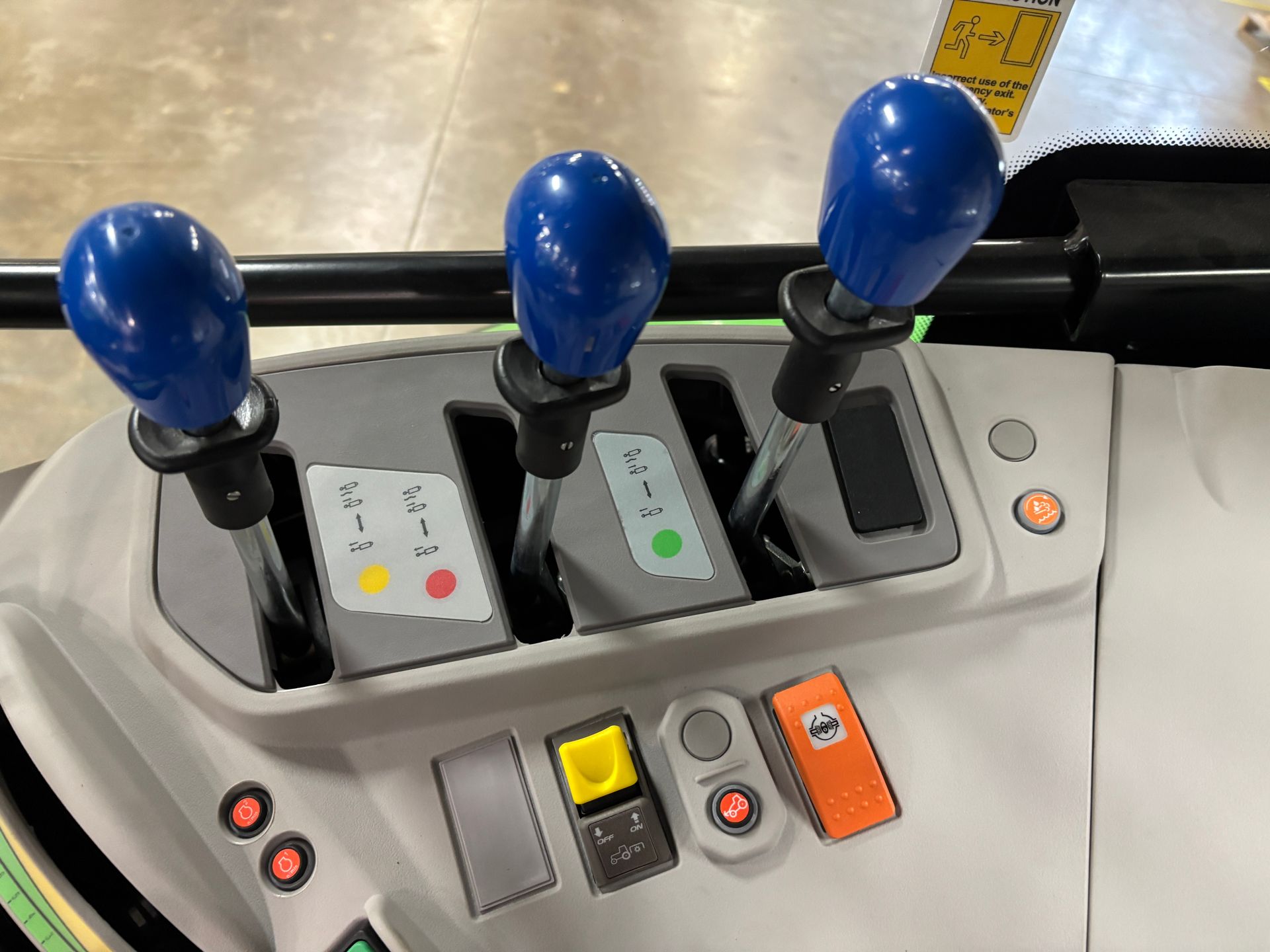 Control panel of a tractor with three blue levers and colored indicator lights.