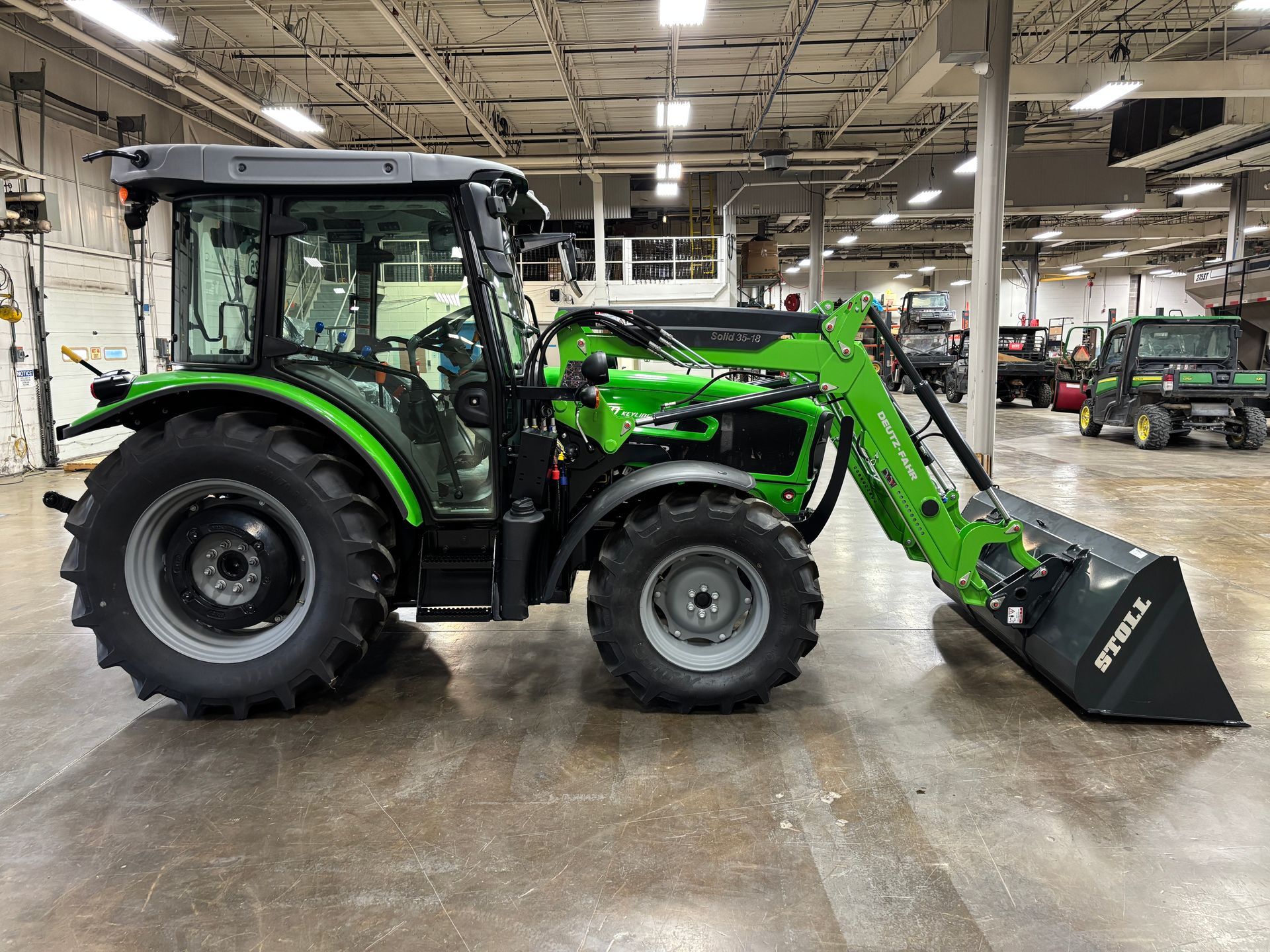 Green tractor with loader inside a showroom.