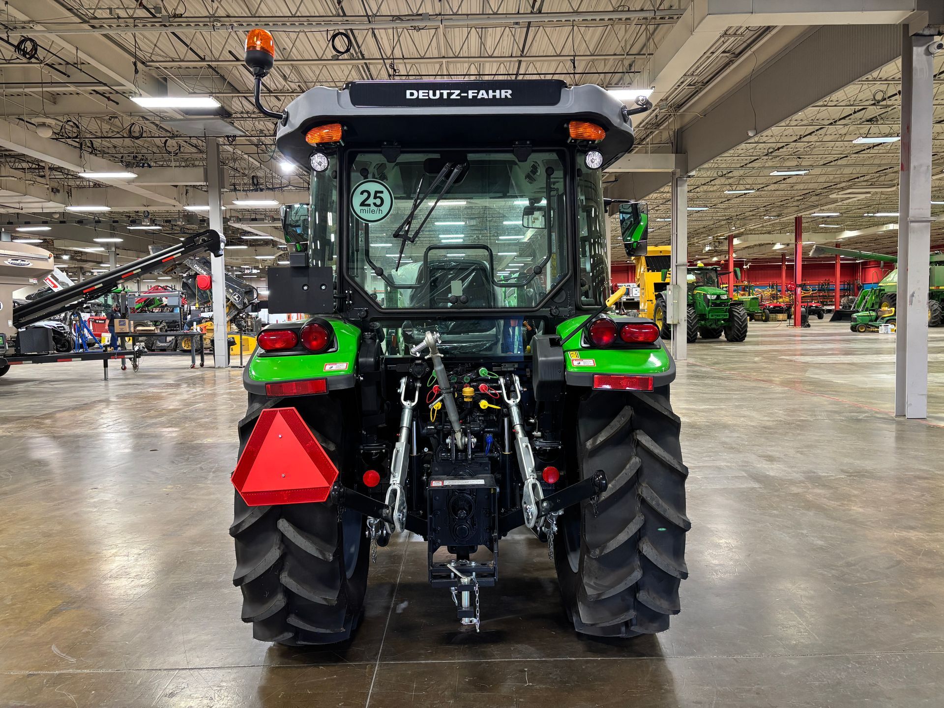 Rear view of a green Deutz-Fahr tractor with black and gray accents, inside a large warehouse.