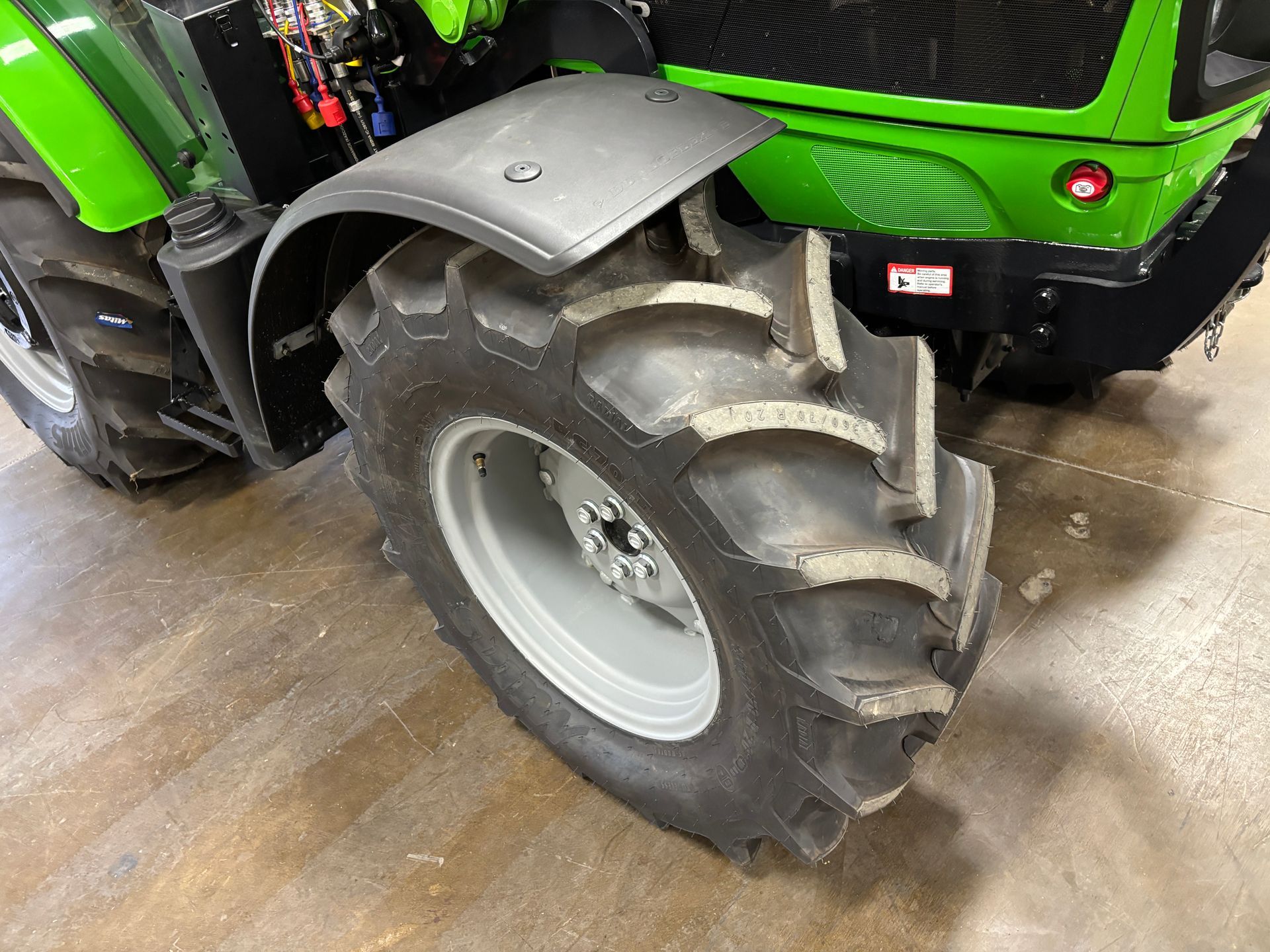 Black tractor tire with grey rim and black fender. Green tractor body visible.