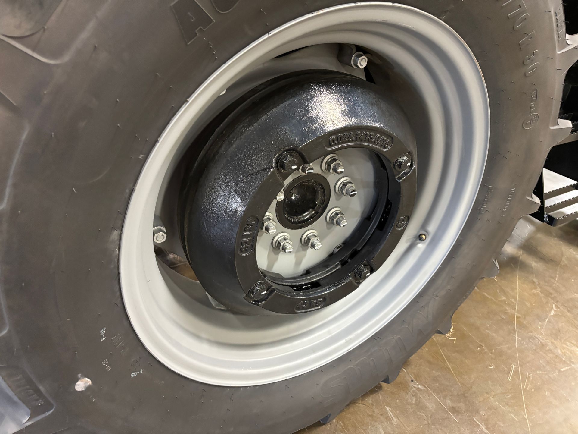 Close-up of a large tractor wheel with a black hub and silver bolts against a gray rim.