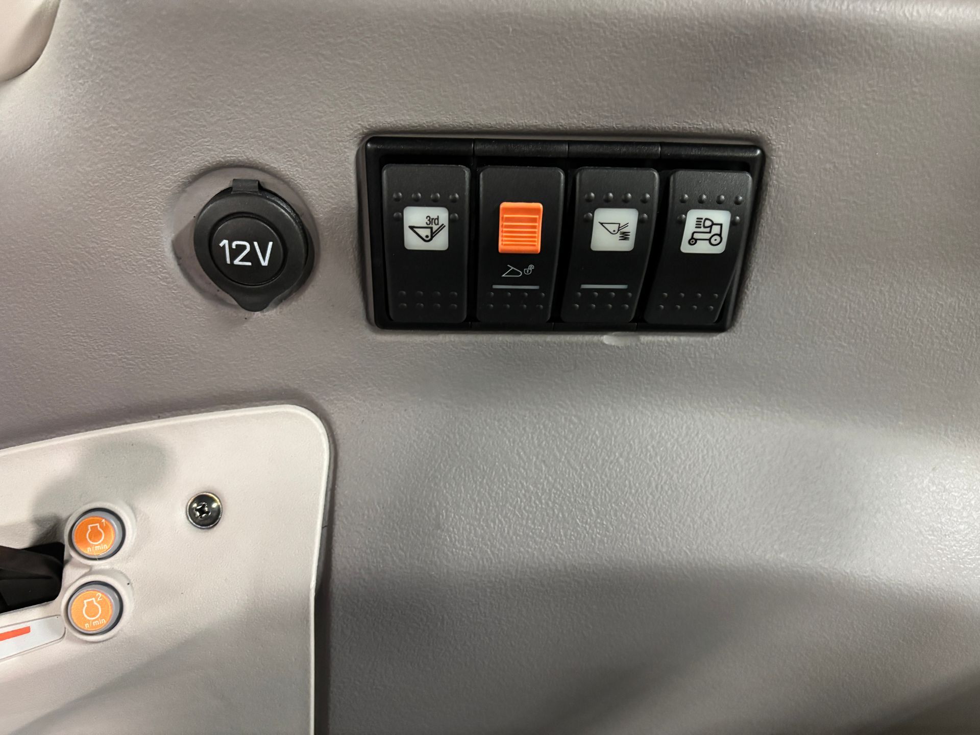 A close-up of a control panel with four black switches and a 12V power outlet.