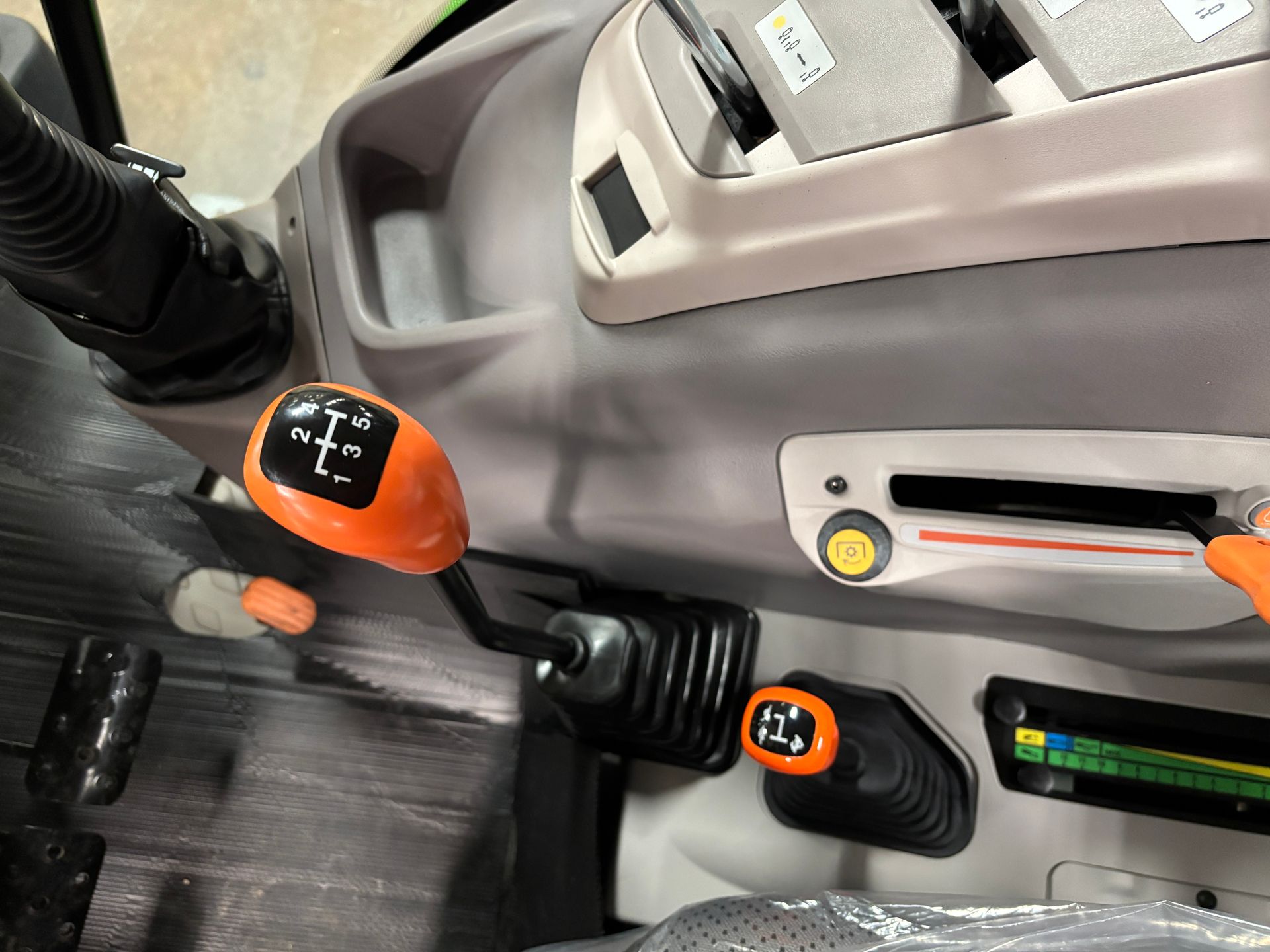 Close-up of a tractor's interior with orange gear levers and dashboard controls.