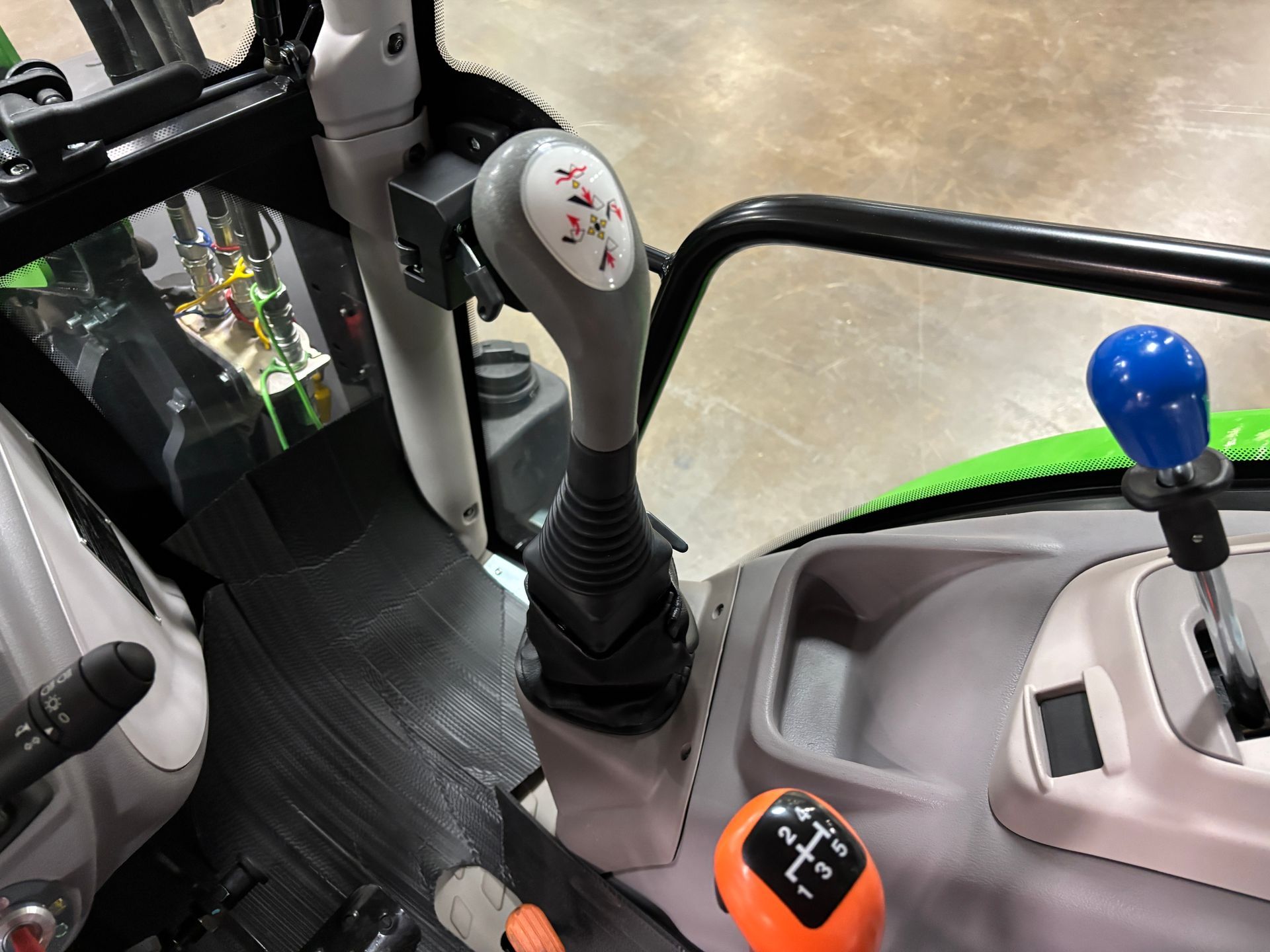 Interior of a tractor cab, featuring gear and joystick controls, with a gray and black color scheme.