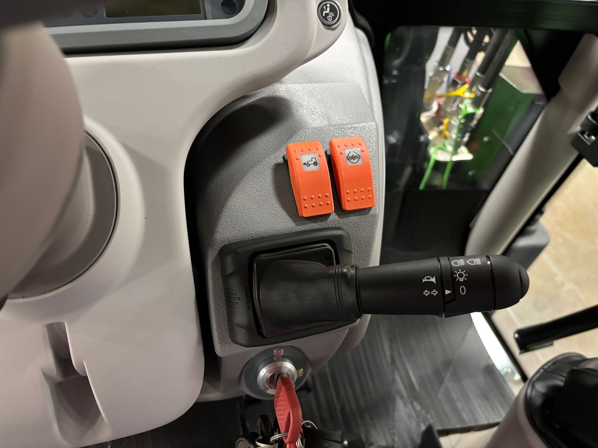 Dashboard with orange switches, lever, ignition, and steering wheel in a vehicle.