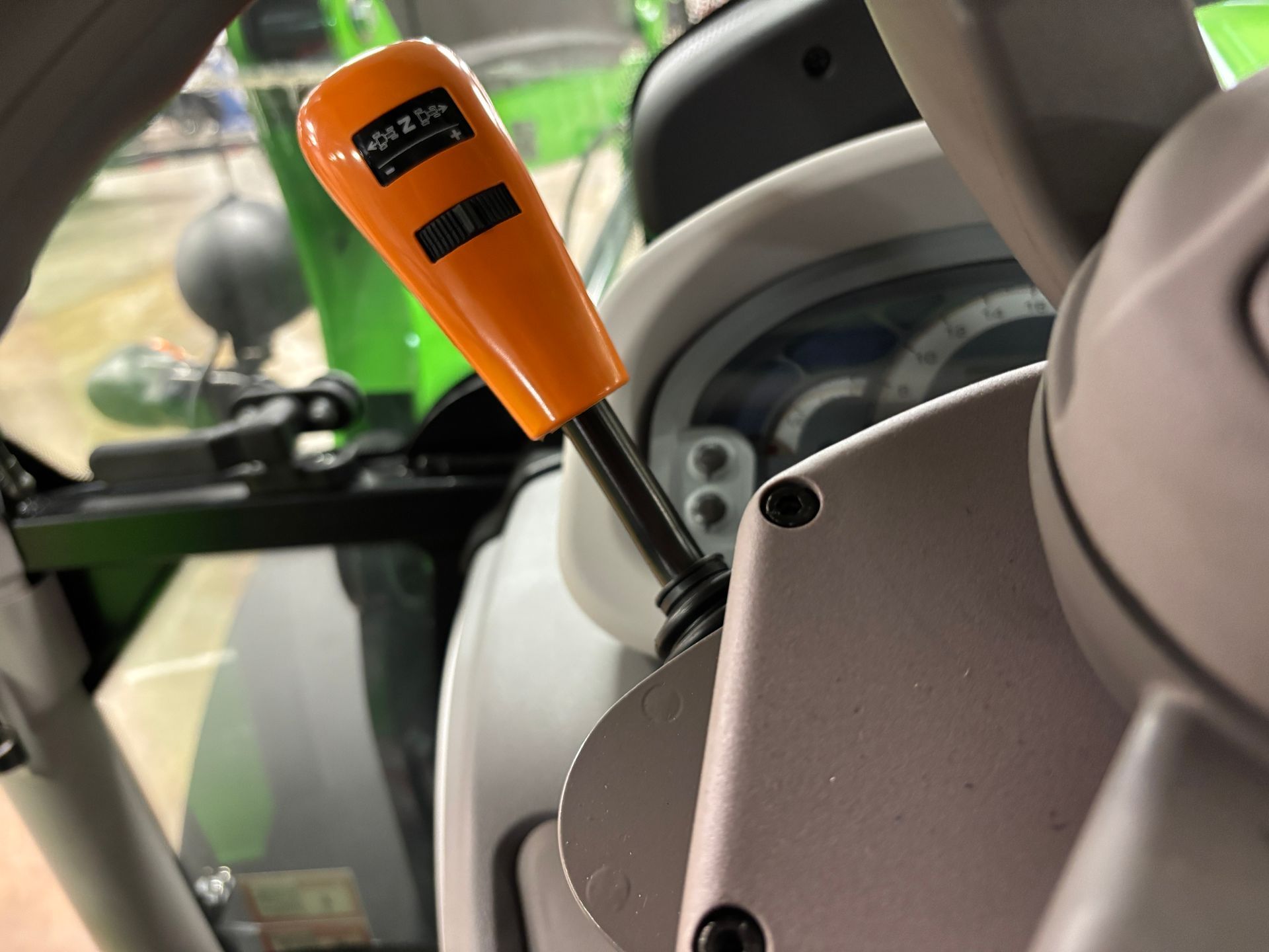 Orange gearshift lever in a tractor cab, next to a dashboard.