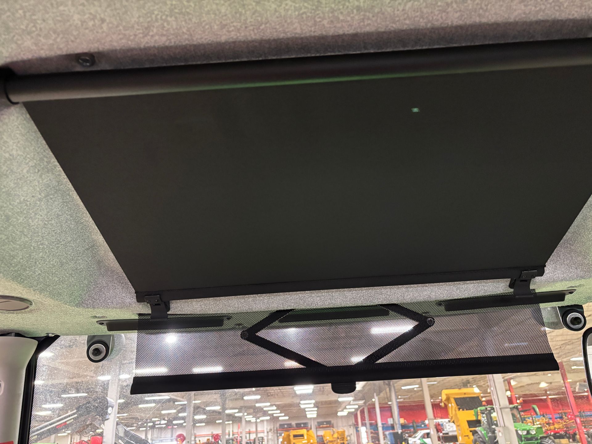 Interior of vehicle cab with black sunshade and patterned front window shade.