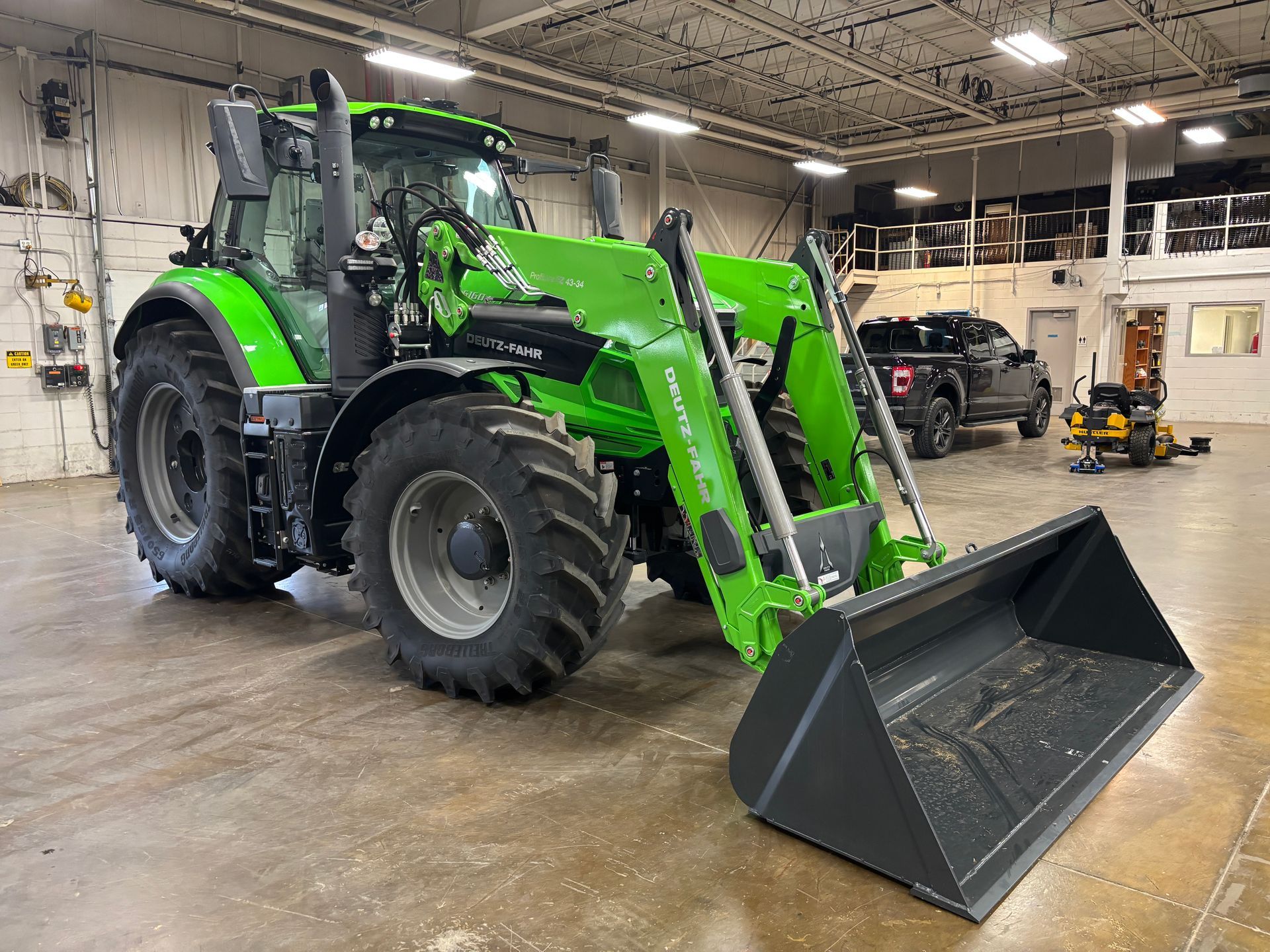 Green tractor with front loader inside a garage.