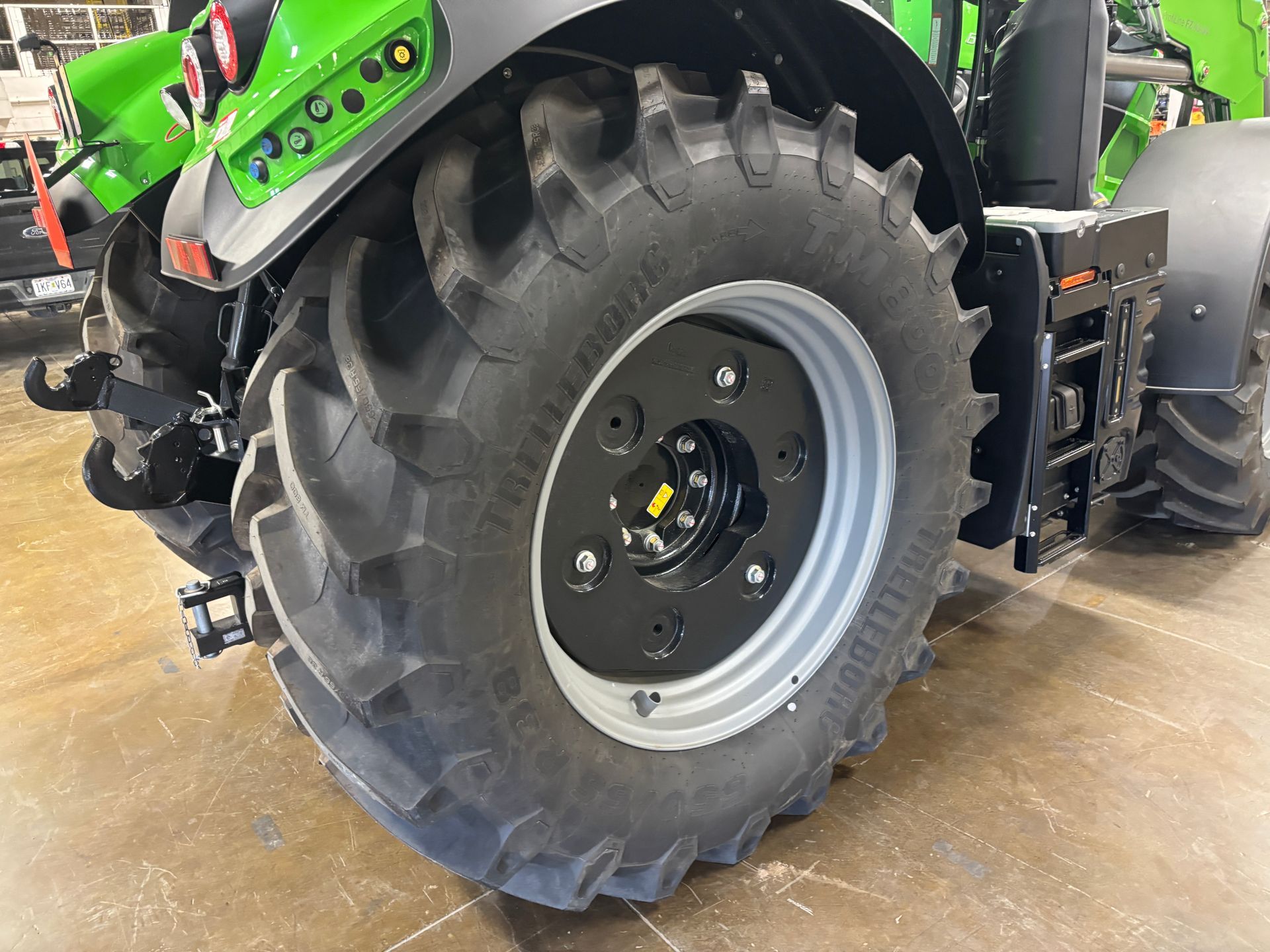 Black tractor wheel and tire, with a silver rim and dark gray tread.