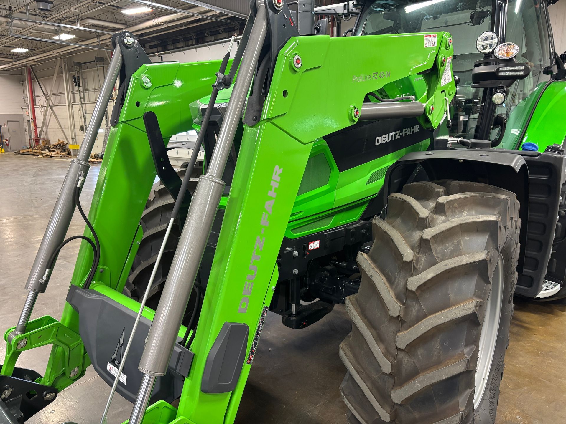 Green Deutz-Fahr tractor with a front loader, parked inside a warehouse.