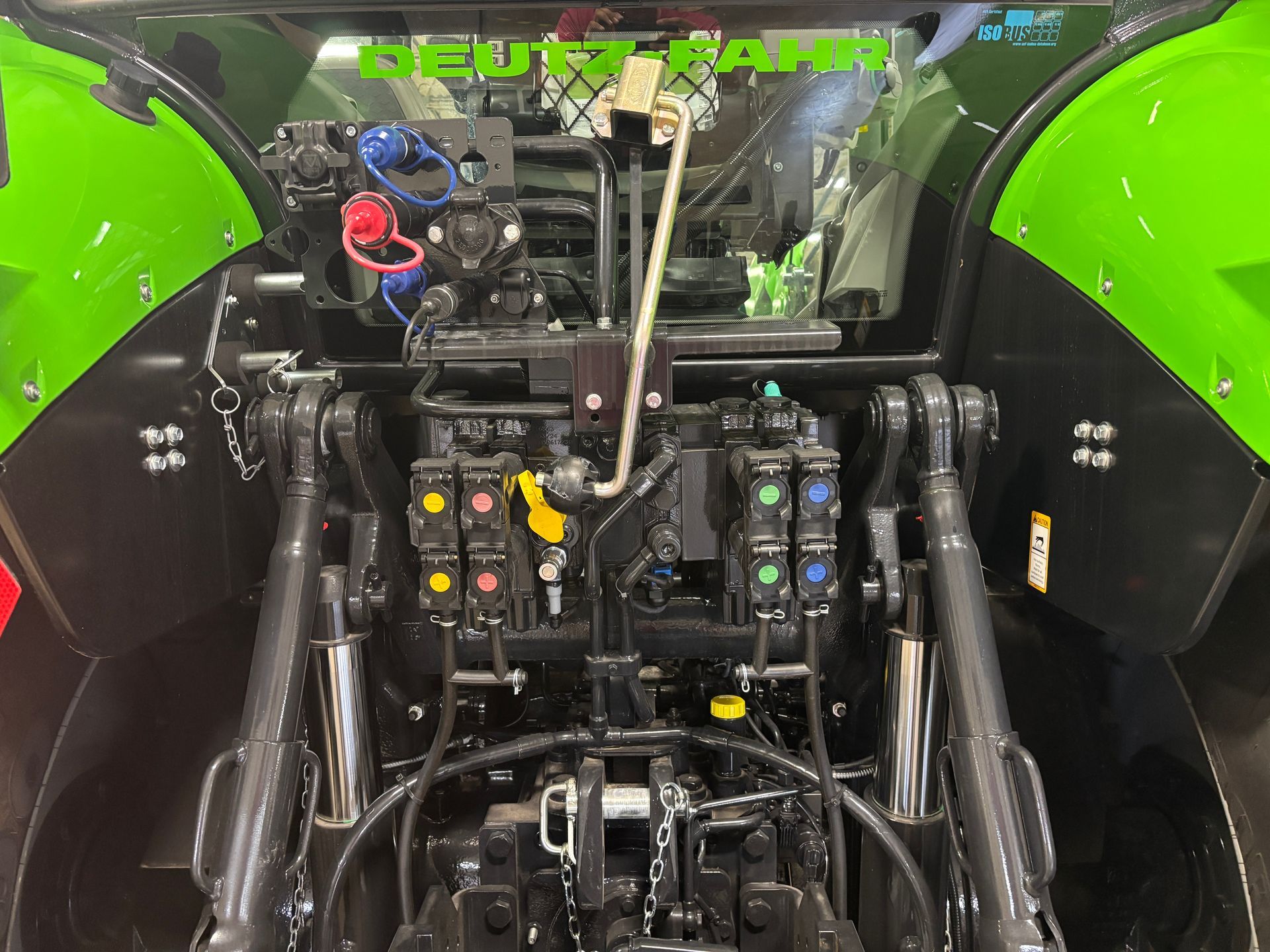 Rear view of a Deutz-Fahr tractor with a complex arrangement of components, including colored connectors and hydraulic controls.