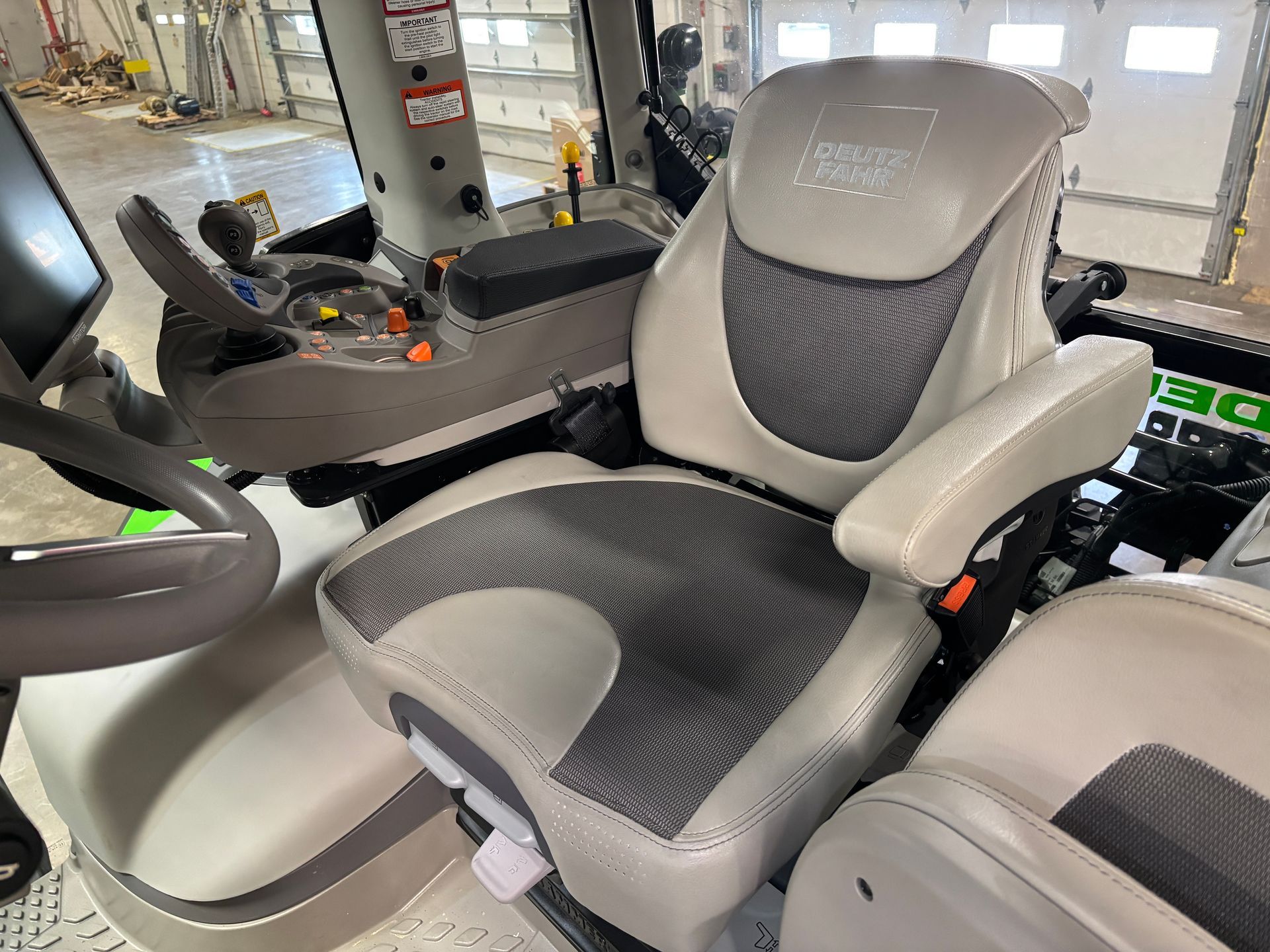 Close-up of a tractor cab interior featuring a gray and black seat with armrests and controls.