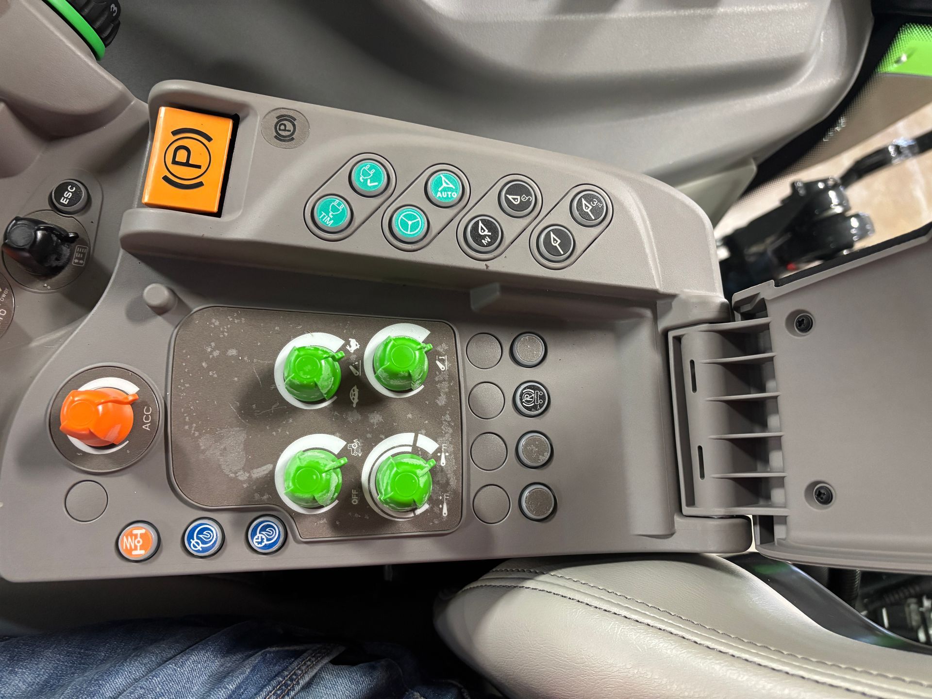 Control panel of a tractor, with green and orange buttons. Gray console.