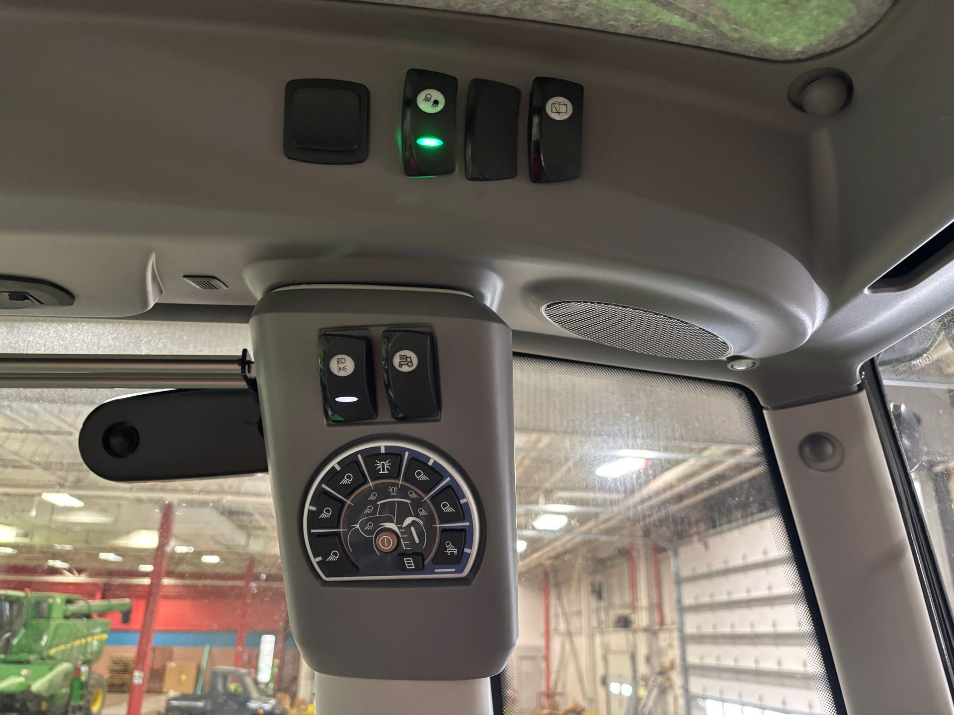 Interior cab view of farm equipment control panel with switches and gauges.