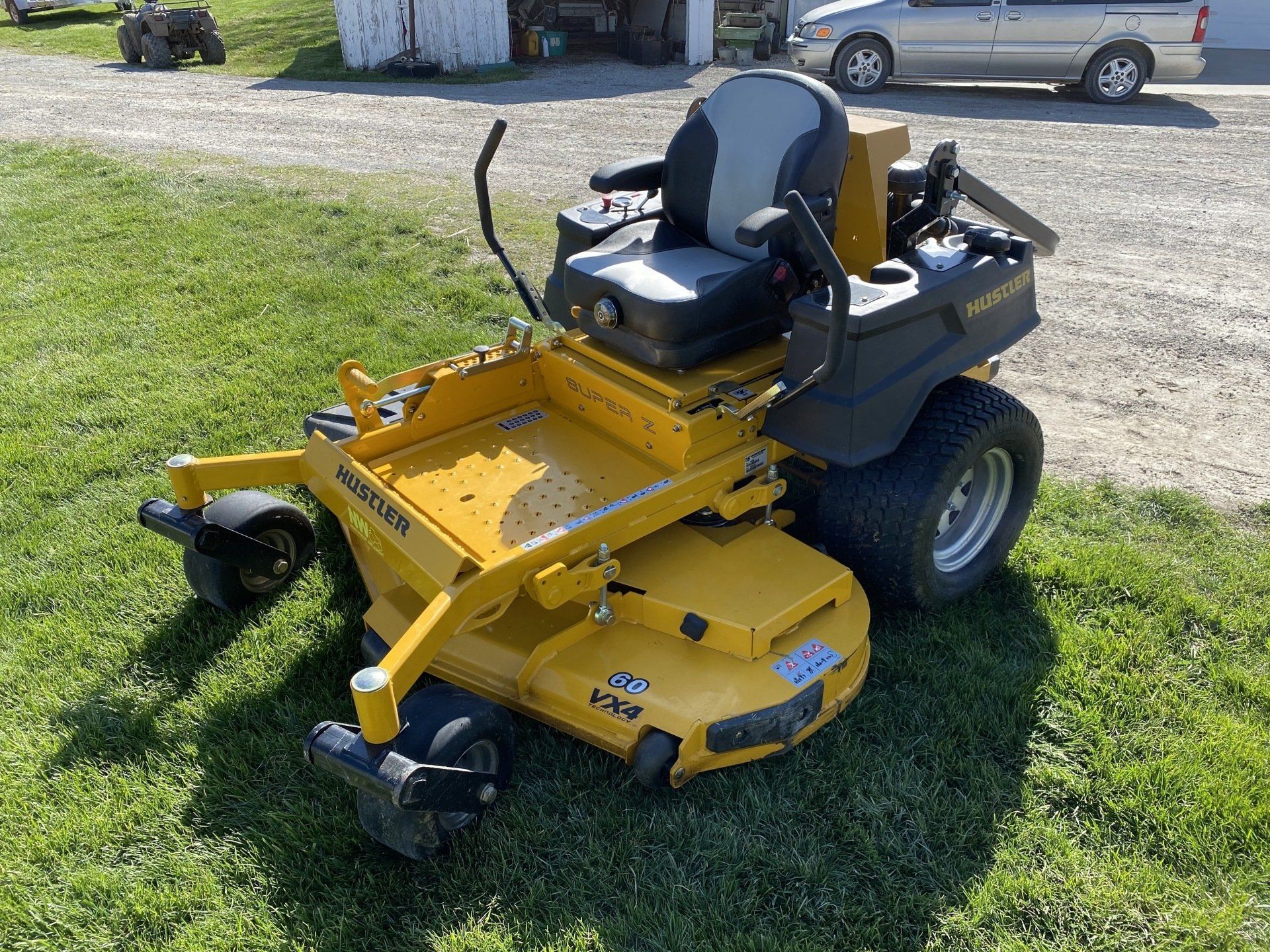 Yellow Hustler zero-turn lawnmower on a grassy lawn.