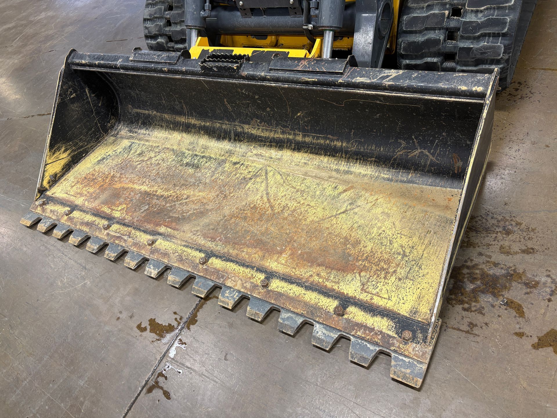 Close-up of a yellow and black construction bucket with teeth, used for digging, inside a machine.