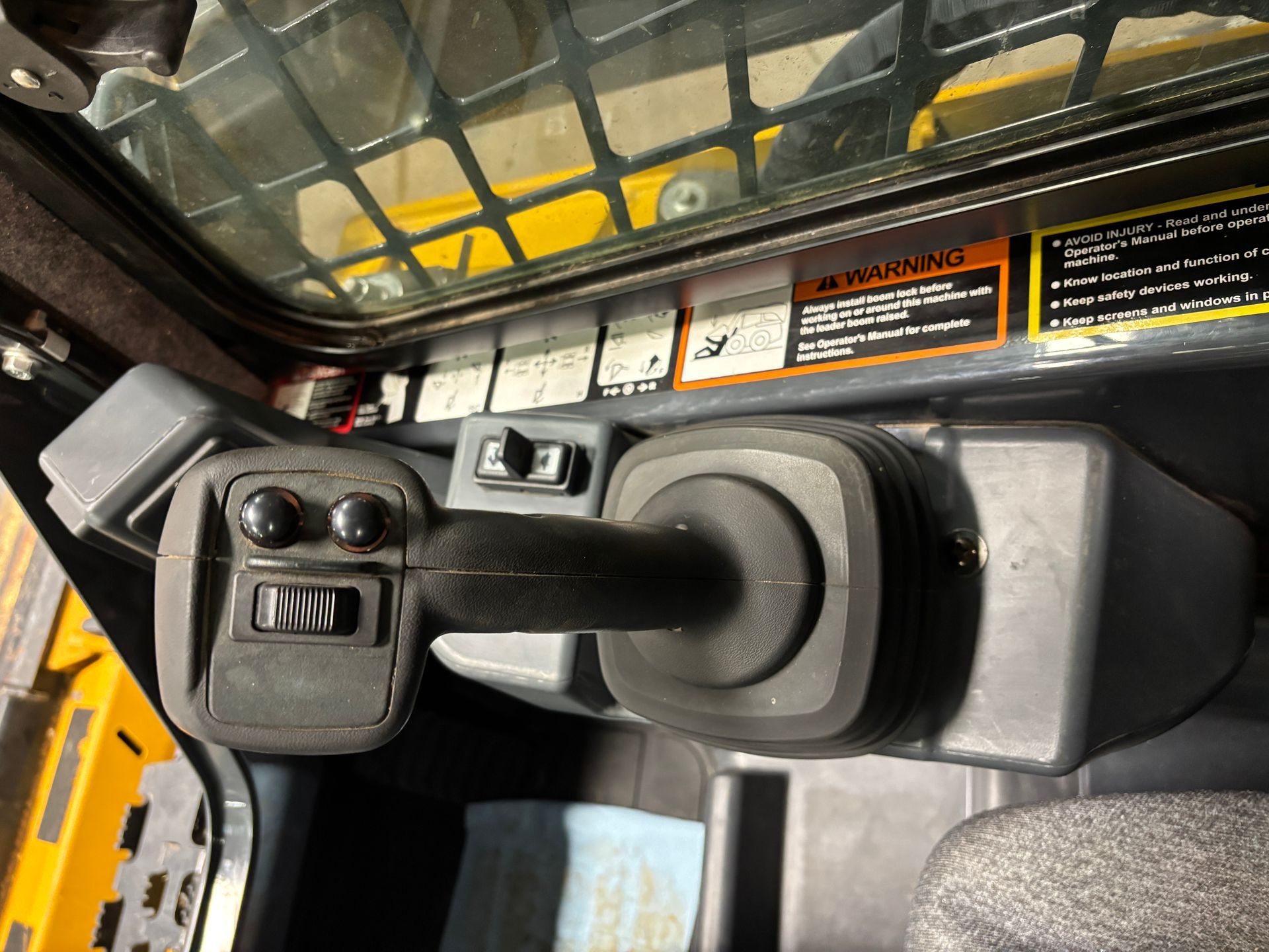 Joystick control panel in a yellow and black construction machine cab.