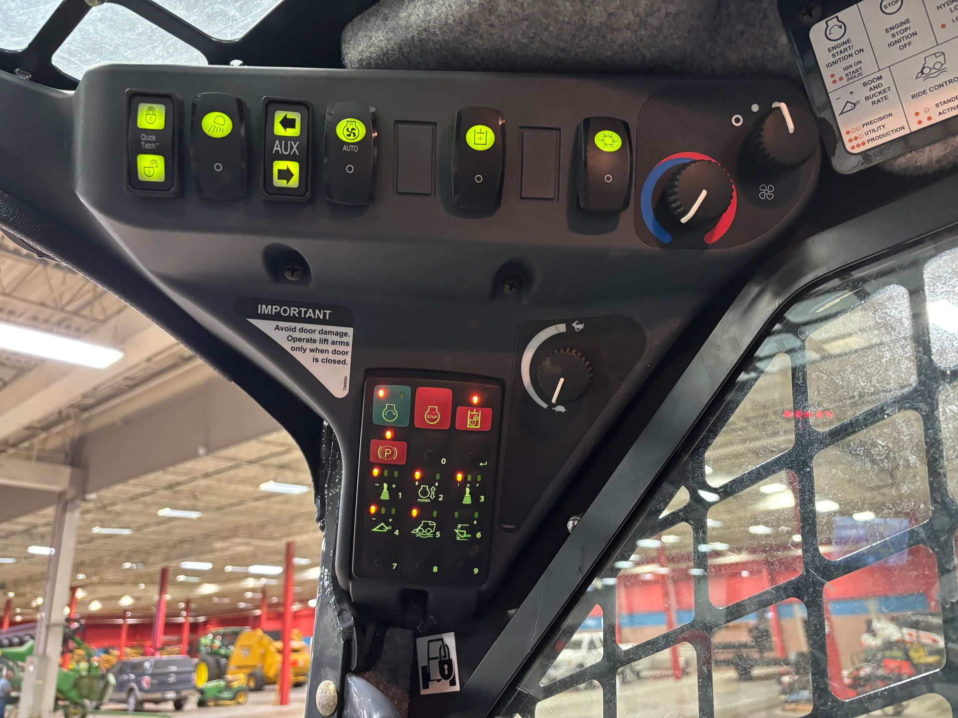 Control panel of a compact track loader, showing switches, lights, and climate controls inside the cab.