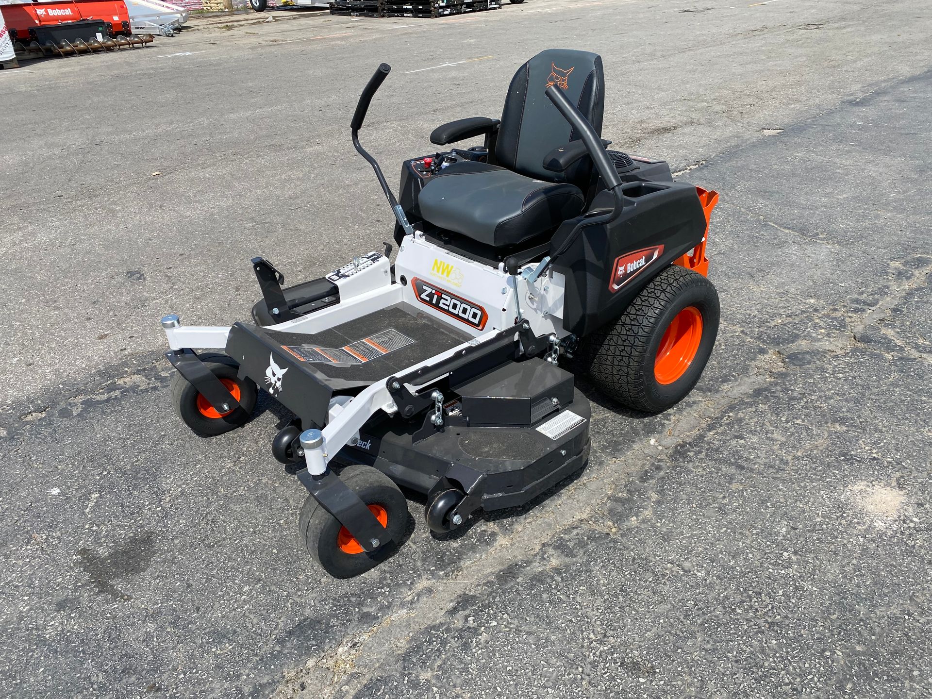 Bobcat zero-turn mower, gray and black with orange wheels, on asphalt.