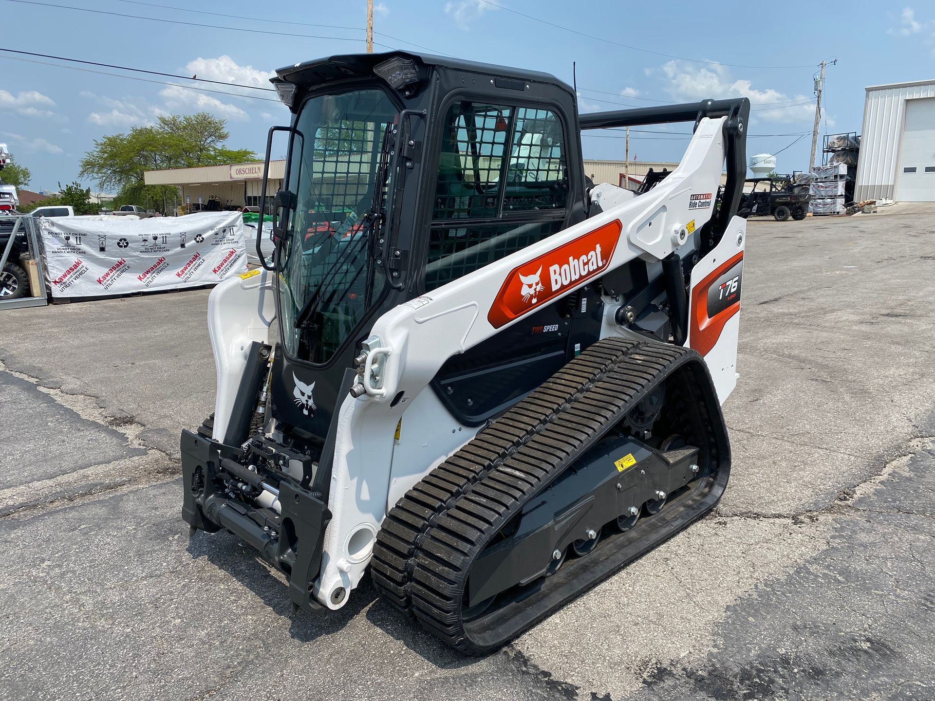 White Bobcat T76 track skid-steer loader on pavement, with black cab and tracks.