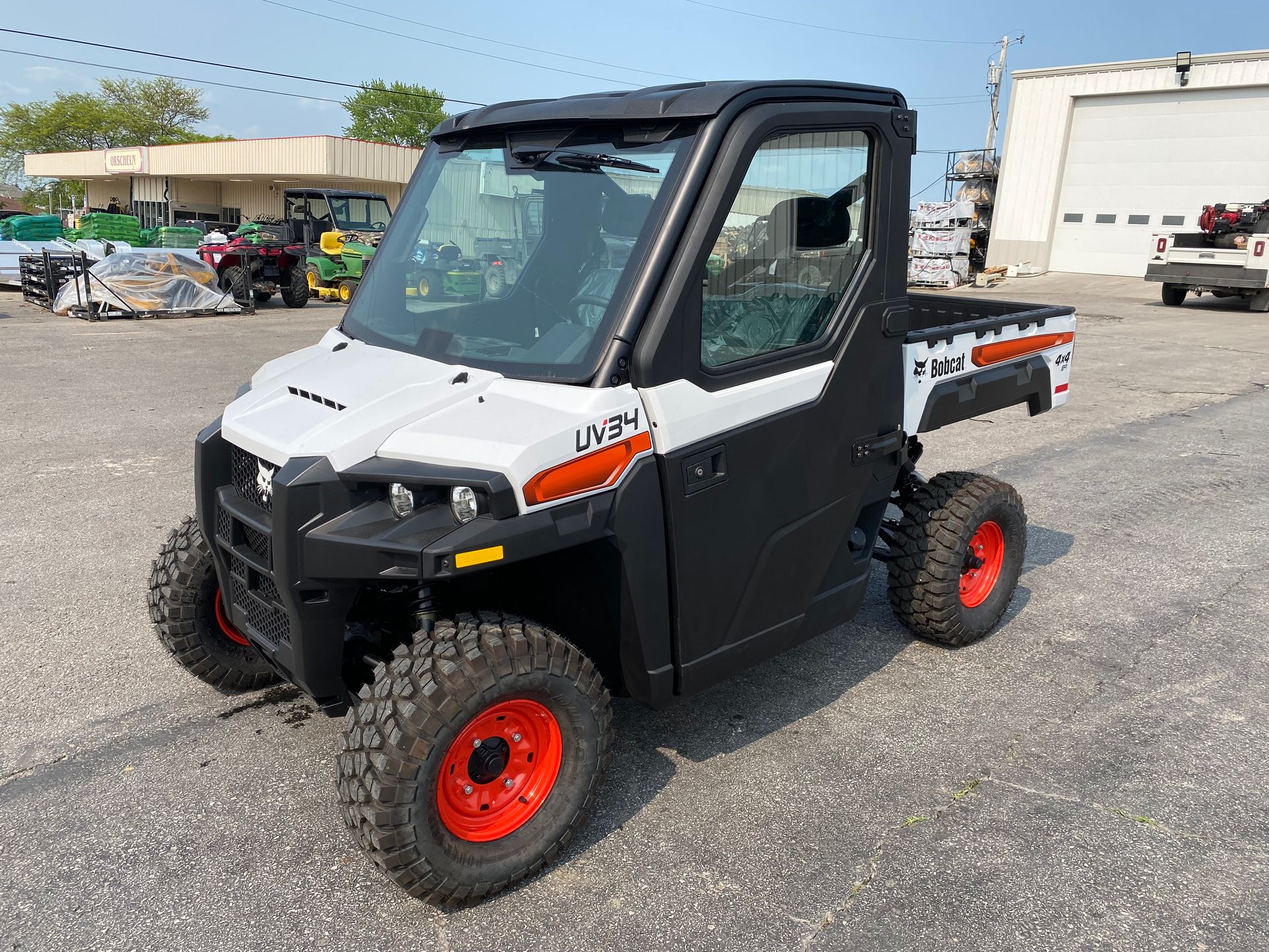 White and black Bobcat UTV with red wheels parked outside.