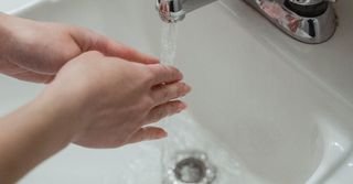 A person is washing their hands in a bathroom sink.