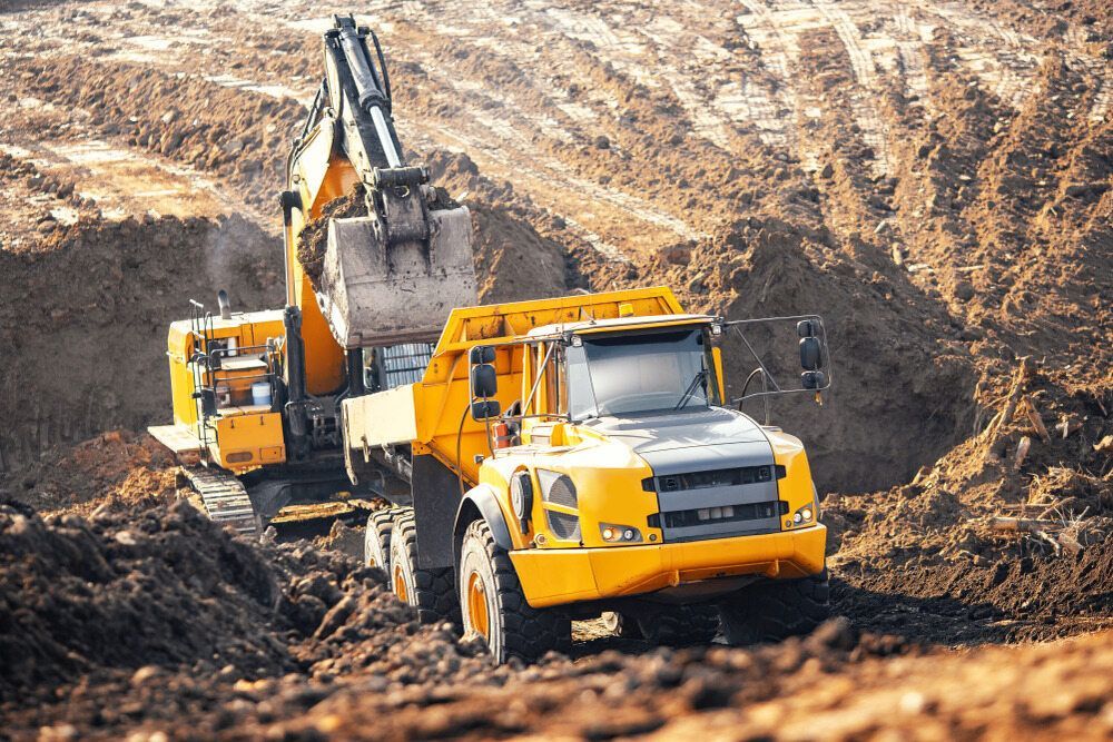 A Dump Truck and an Excavator Are Driving Through a Dirt Field — Koumala Quarry In Sarina, QLD