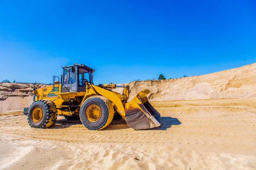 A Yellow Construction Vehicle Parked in a Sand Area — Koumala Quarry In Koumala, QLD