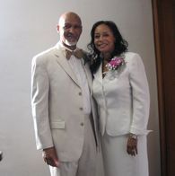 a man and a woman in white suits are posing for a picture .