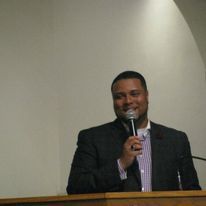 a man in a suit is standing at a podium holding a microphone .