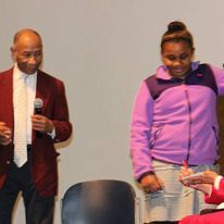a man in a suit and tie is standing next to a woman in a purple jacket .