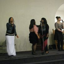 a group of women are singing into microphones on a stage .