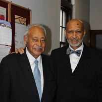 two men in suits and bow ties are posing for a picture .