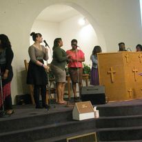 a group of women are singing into microphones in a church .