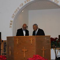 two men are standing at a podium in a church .