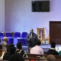 a man is speaking into a microphone in front of a group of people in a church .