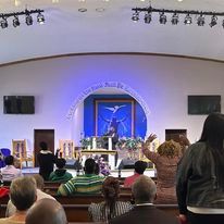 a group of people are sitting in a church watching a sermon .