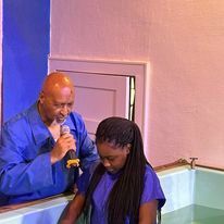 a man is speaking into a microphone while a woman is sitting in a bathtub .