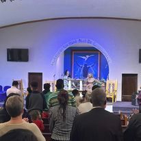 a group of people are sitting in a church watching a service .