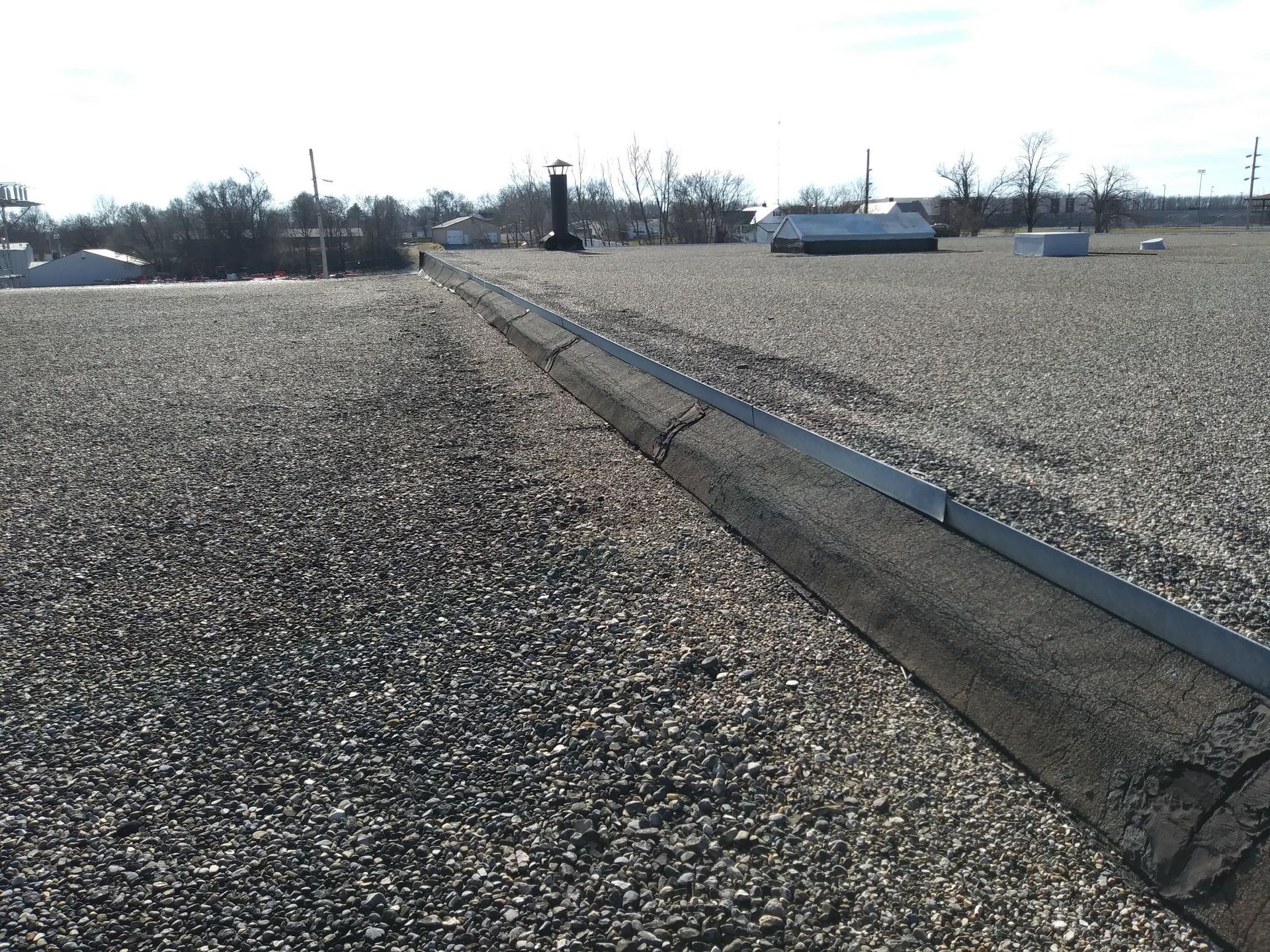 A gravel road with a drain on the side of it