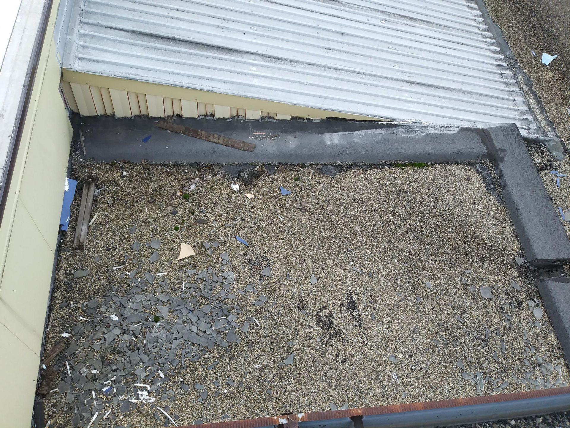 An aerial view of a roof with a metal roof and a gravel roof.